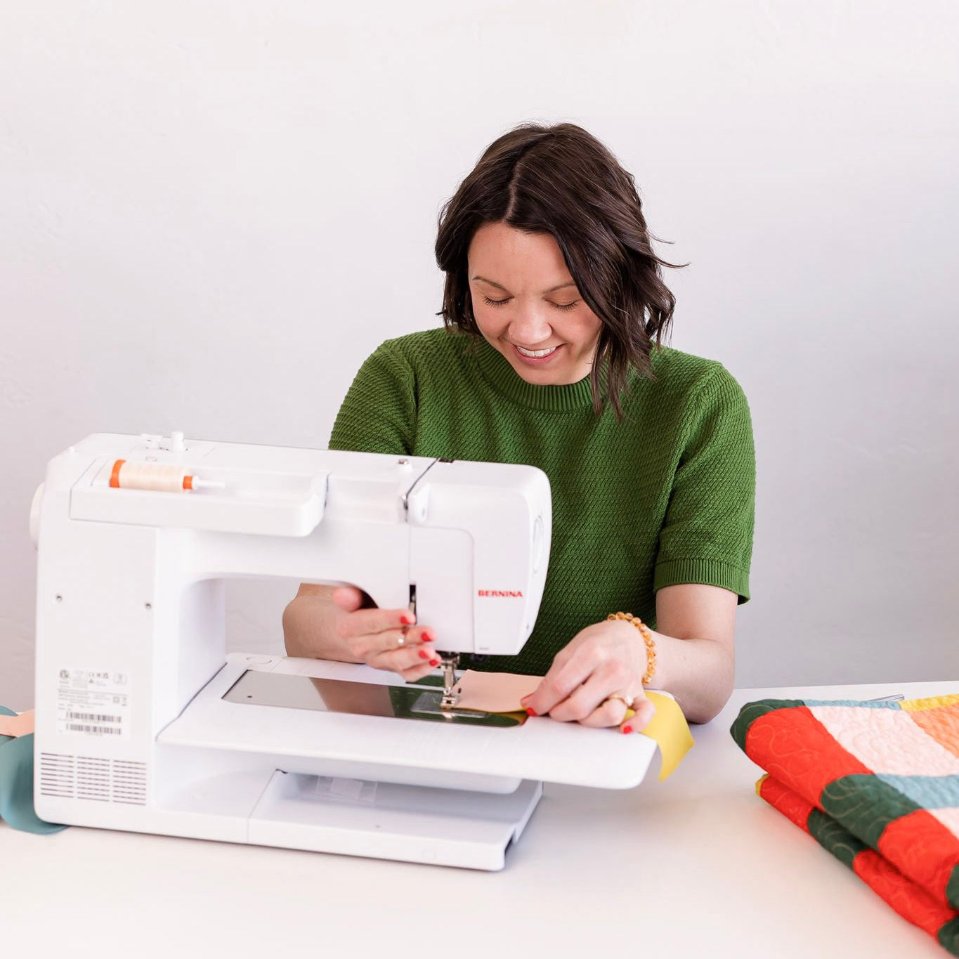 Woman using a sewing machine with a white background