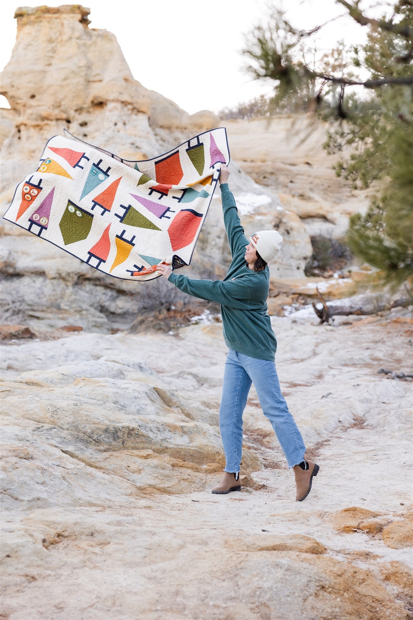 Person holding a colorful patterned blanket in a natural rocky landscape