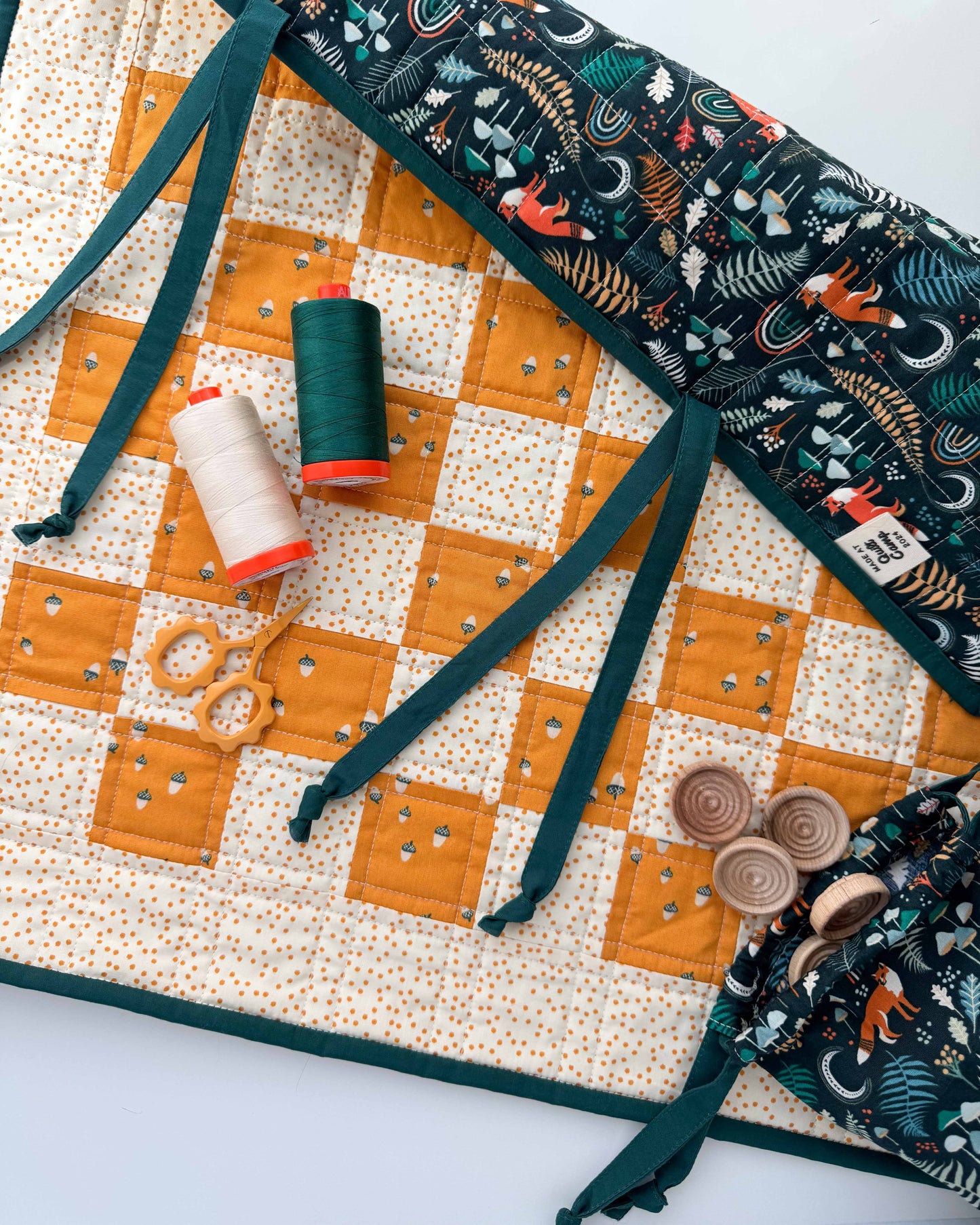 Quilted checkerboard with sewing accessories on a white background