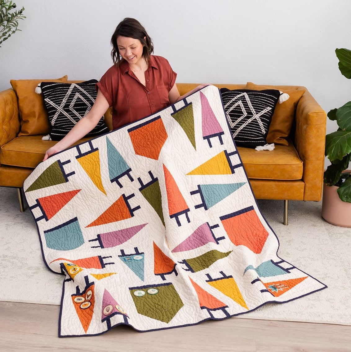 Person holding a colorful quilt in a living room setting